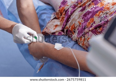 Close view of gloved hands starting peripheral IV in an adult patient in a clean hospital setting with copy space
