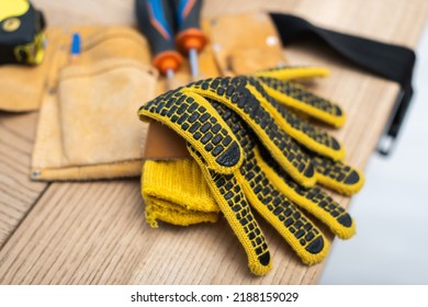 Close Up View Of Gloves Near Blurred Tool Belt On Table