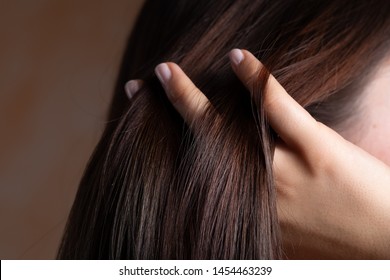 A close up view of a gorgeous young brunette lady with lacquered nails. Combing her fingers through the straight, sleek and conditioned hair. Copy space on the left.