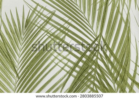 A close up view of a green palm leaf pattern printed on a textured wallcovering surface.