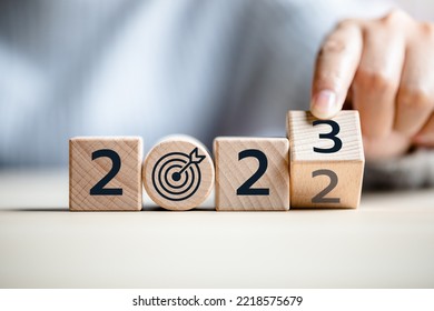 Close Up View Of Hand Flipping Cube Wooden 2022 To 2023 With Dartboard Icon, The End Of 2022 And The New Beginning In 2023, Concept Of Happy New Year, New Project, Opportunity, Goals, Strategy.