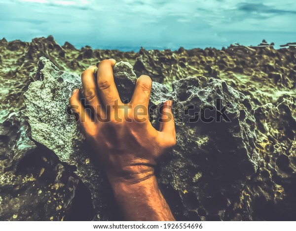 Close view of hand on Mystic dark moon surface.\
Astrology, astronomy, paranormal activity concept or scary\
supernatural planet landscape. Dramatic toned photo of natural\
textures black coral