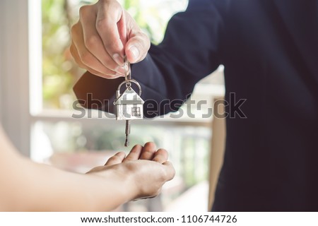 close up view hand of property realtor / landlord giving key house to buyer / tenant.