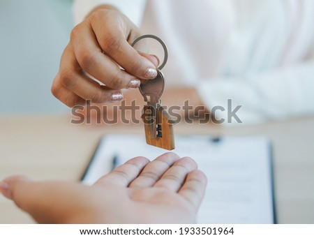 close up view hand of property realtor landlord giving key house to buyer tenant.