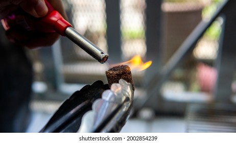 Close Up View Of Hand Using A Gas Lighter Starter To Ignite Camping Charcoal Cock Fire Starter For Barbeque Party.