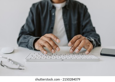 Close up view of hands of African American businessman or student in grey shirt typing on keyboard while working at desk in office, distantly learning, online education or business meet