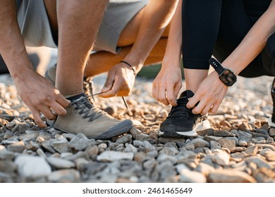 Close up view of hands of athletic man in white t-shirt and woman in black top tying shoelaces before exercising on roof terrace. - Powered by Shutterstock