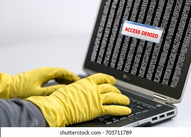Close up View of Hands of Hacker working on Laptop to hack the Account password using yellow latex Gloves to avoid leaving fingertips