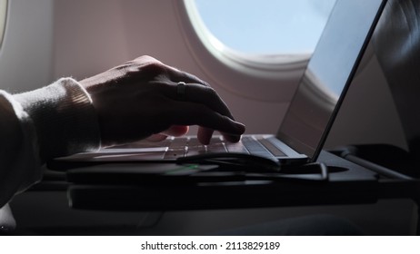 Close Up View Of Hands Man Typing Text On Computer, Flying In Airplane. During Business Trip, Businessman Is Not Distracted From Work And Writes Letter While Sitting On Laptop In Airplane. Rack Focus.