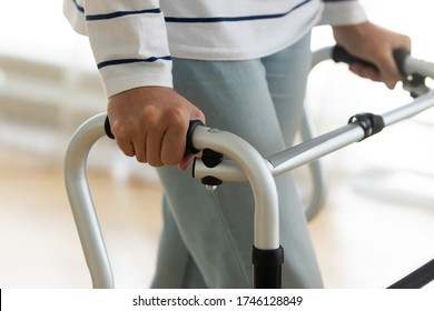 Close up view hands of old disabled woman holding walking frame makes exercises regain leg strength after operation, injury, accident. Safe design equipment, part of rehabilitation programme concept - Powered by Shutterstock