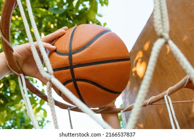 Close View Of Hands Throwing A Ball Into A Basketball Basket, Teenage Boy Playing At Home In The Backyard, Outdoor Activities On Summer Vacation