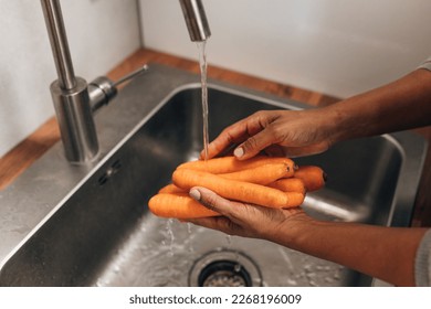 Close up view of woman’s hands washing carrots in the sink - Powered by Shutterstock