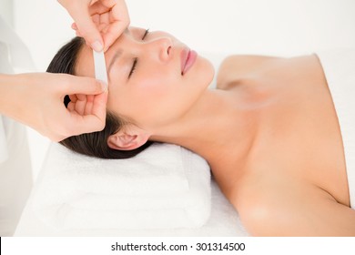 Close up view of hands waxing beautiful womans eyebrow