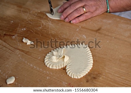 Close view of the hands of a woman that decorates a traditional sardinian  bread sweet