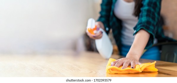 Close Up View Of Happy Woman Clean Home Or Restaurant. She Wiping Dust Using Spray And Orange Fabric Cleaning On Dirty Table. House Keeping Maid Cleaning Service Job To Prevent Covid19 Virus Outbreak.