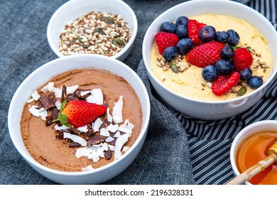 Close View Of Healthy Cereal Bowls Containing Oats And Berries With A Bowl Of Honey On The Side