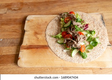 A Close Up View Of A Healthy Ham And Salad Whole Wheat Wrap On A Wooden Cutting Board 