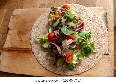 A Close Up View Of A Healthy Ham And Salad Whole Wheat Wrap On A Wooden Cutting Board 