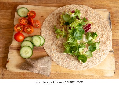 A Close Up View Of A Healthy Ham And Salad Whole Wheat Wrap On A Wooden Cutting Board 