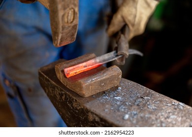 Close up view of heated metal and anvil. The blacksmith in the production process of metal products handmade in the forge. Blacksmith forging metal with a hammer. Metal industry, old profession - Powered by Shutterstock