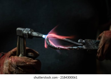 Close up view of heated metal and fire burner. Blacksmith in the production process of other metal products handmade in the forge. Metalworker forging metal into knife. Metal craft industry.
