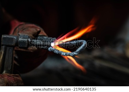 Close up view of heated metal and fire burner. Blacksmith in motion of the production process of other metal products handmade in the forge. Metalworker forging metal into knife. Metal craft industry.