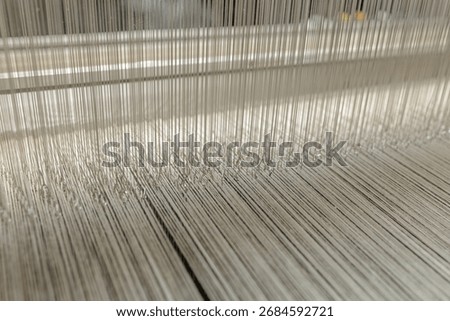 Close view of heddles and warp threads on a modern loom in a textile factory showing precision weaving and quality production