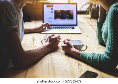 Close Up View Of Hipster Friends Watching Video In Social Network Via Portable Net-book, While Sitting At Wooden Table In Coffee Shop. Group Of People Are Reading News Information On Laptop Computer