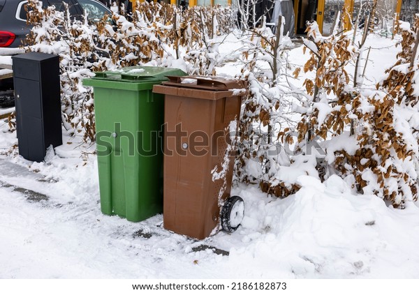 Close up view of\
house mail post box and waste and recycling containers on snowy\
bushes background. Sweden.\
