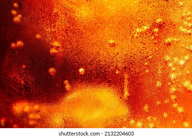 Close up view of the ice cubes in dark cola background. Texture of cooling sweet summer's drink with foam and macro bubbles on the glass wall. Fizzing or floating up to top of surface.