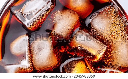 Close up view of the ice cubes in dark cola background. Texture of cooling sweet summer's drink with foam and macro bubbles on the glass wall. Fizzing or floating up to top of surface.