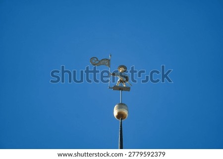 Close up view of the iconic Old Thomas weather vane in Tallinn, Estonia. A historic golden symbol of the city standing tall against a vibrant and clear blue sky.