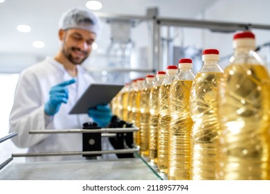 Close up view of industrial vegetable oil production and bottles filled with sunflower oil being transporter on automated conveyor machine.