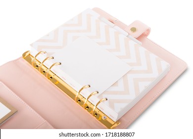 A close view of an inside part of an open light pink leather daily agenda with gold rings and golden press stud isolated on a white background.