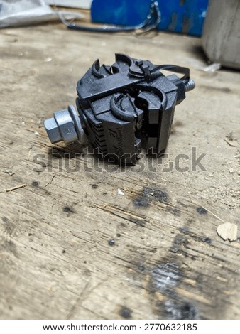 Close view of an insulation piercing connector on top of a wooden working table