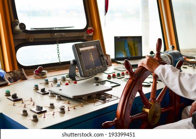 Close view into captain's cabins, navigation equipment and captain's hand on rudder during cruising 