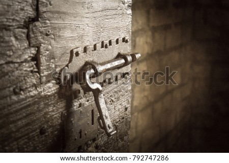 Close up view of an iron latch on an old door in a dungeon or in a castle. Vignette effect.