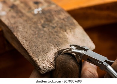 Close up view of a jeweller using tweezers to place a gem on a silver ring in a craftsman's workshop - Powered by Shutterstock