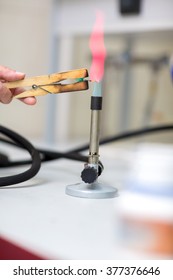 Close Up View Of Laboratory Burner And Tongs Holding Needle In Chemistry Lab