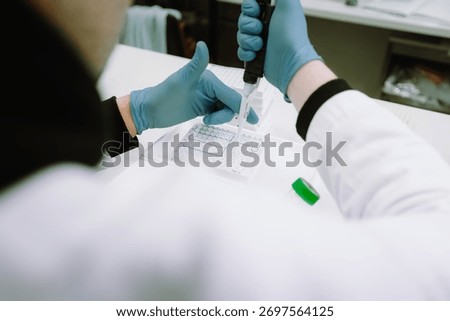 Close view of laboratory worker performing careful pipetting procedure during controlled scientific analysis.