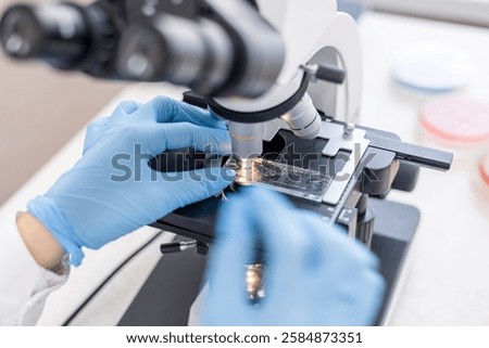 Close up view of laboratory worker using microscope and examines fragments of tissue. Examination under microscope. Test sample under the microscope in laboratory. Microbiology research