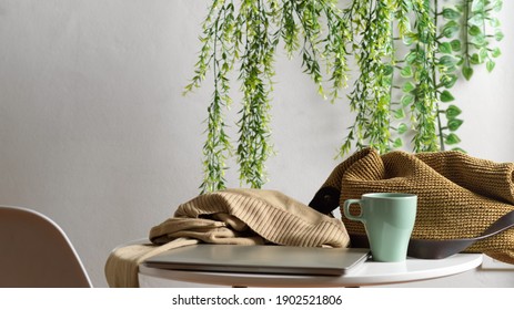 Close up view of laptop, mug, sweater and bag on the coffee table in Biophilia leisure corner  - Shutterstock ID 1902521806