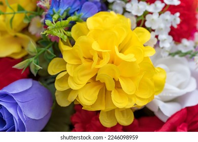 Close view of a large yellow artificial flower surrounded by smaller flowers. - Shutterstock ID 2246098959