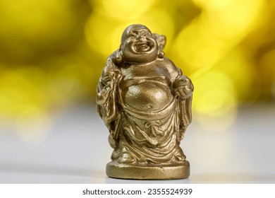 Close up view of Laughing Buddha statue  against golden background.