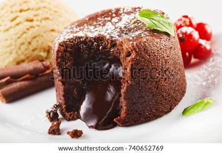 Close up view of lava cake filled with chocolate against ice cream and berries