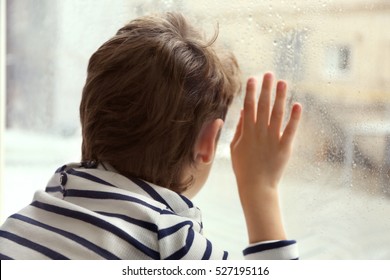 Close up view of little boy looking out of window