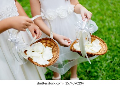 Close Up View Of Little Flower Girls Tossing Rose Petals During Wedding Ceremony.