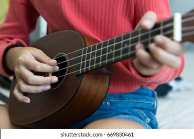 Close up of view of little girl's hand playing ukulele