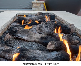Close view of logs burning in a large, white, stone fire pit