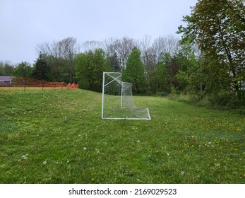 A Close Up View Looking Through A Large Soccer Net. To The Left Is Another Net And Directly In Front, Across The Field, Is The Opponent's Soccer Goal Net. They Are White And Big.